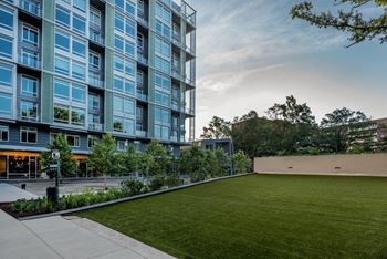 A grassy area with a large building at Valo Apartments, Washington, 20024